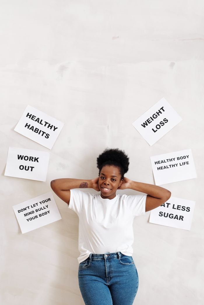 services-03 Woman standing against a wall with motivational slogans promoting health and fitness.